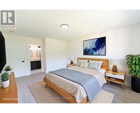 A bedroom with a bed, nightstand, and a painting on the wall.