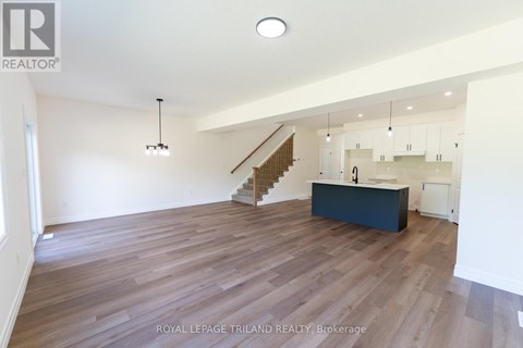 A spacious room with wooden flooring and a staircase leading to the upper level.