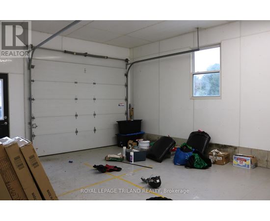 A room with a white wall and a window with a view of trees outside.
