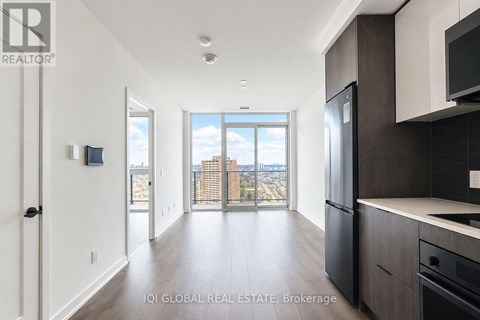 A modern kitchen with dark wood cabinets and a large window overlooking the city.