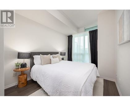 A bedroom with a white bed and a black headboard.