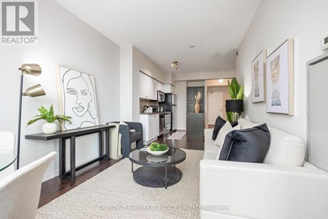 A living room with a white couch, a coffee table, and a painting on the wall.