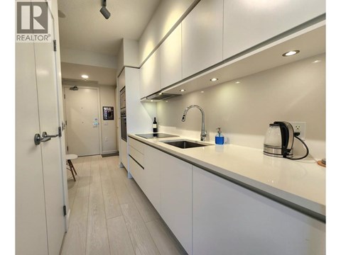 A modern kitchen with white cabinets and a sink.