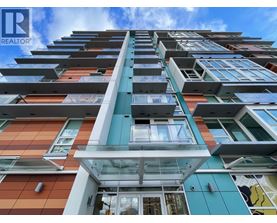A tall, modern building with a glass entrance and balconies on each floor.