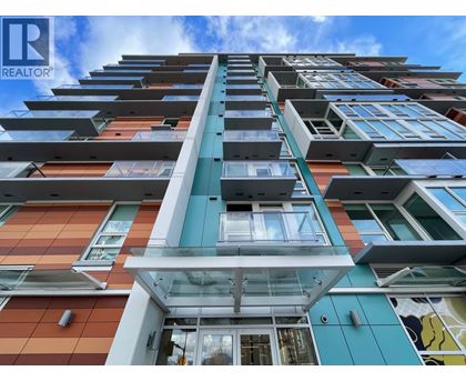 A tall, modern building with a glass entrance and balconies on each floor.