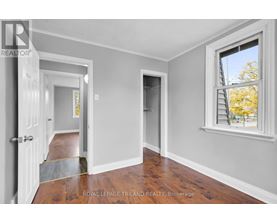 A room with a doorway leading to another room and a window with a view of trees outside.