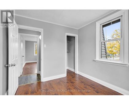 A room with a doorway leading to another room and a window with a view of trees outside.