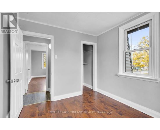 A room with a doorway leading to another room and a window with a view of trees outside.