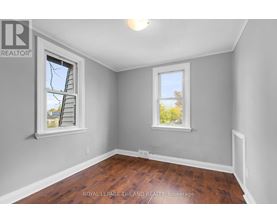 A room with a wooden floor and two windows.