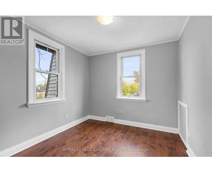 A room with a wooden floor and two windows.