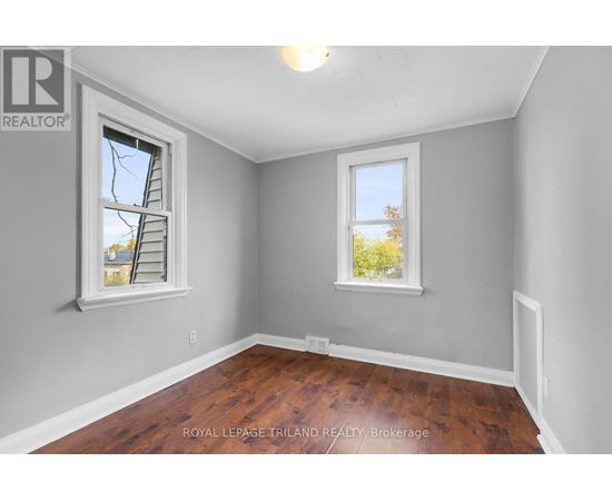 A room with a wooden floor and two windows.