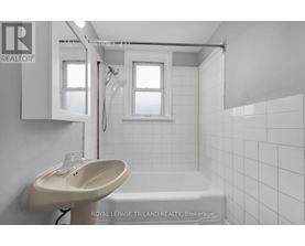 A white bathroom with a sink, mirror, and bathtub.
