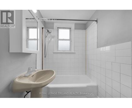A white bathroom with a sink, mirror, and bathtub.