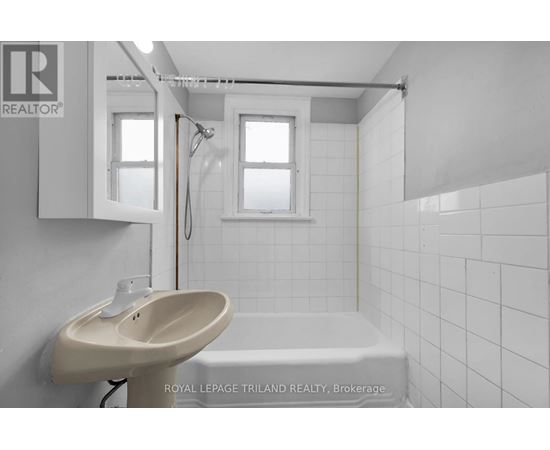 A white bathroom with a sink, mirror, and bathtub.