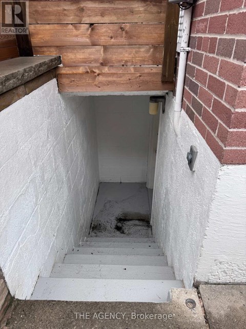 A small white doorway with stairs leading down to a dark area.