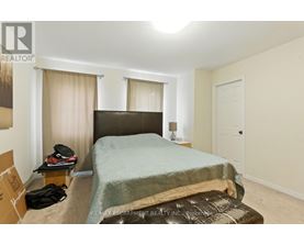 A bedroom with a bed, nightstand, and window with curtains.