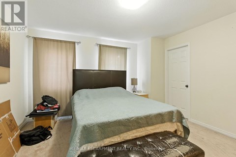 A bedroom with a bed, nightstand, and window with curtains.