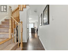 A hallway with a staircase and a framed picture on the wall.