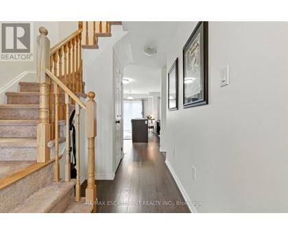 A hallway with a staircase and a framed picture on the wall.