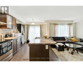 A modern kitchen with a wooden island and a dining area with a black couch.