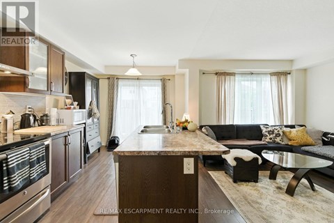 A modern kitchen with a wooden island and a dining area with a black couch.