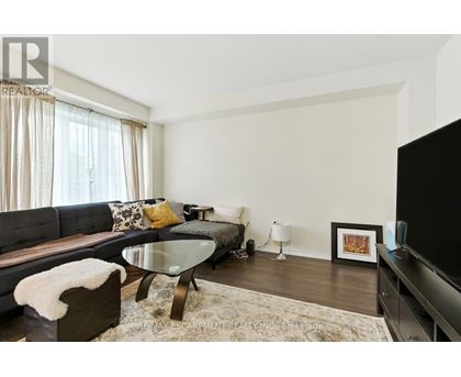 A modern living room with a glass table and a grey couch.