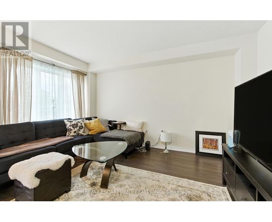 A modern living room with a glass table and a grey couch.