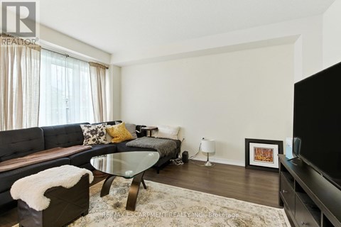 A modern living room with a glass table and a grey couch.