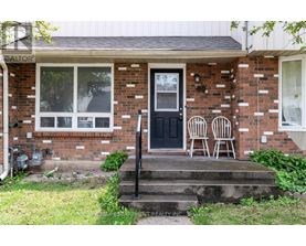 A house with a black door and two chairs on the porch.