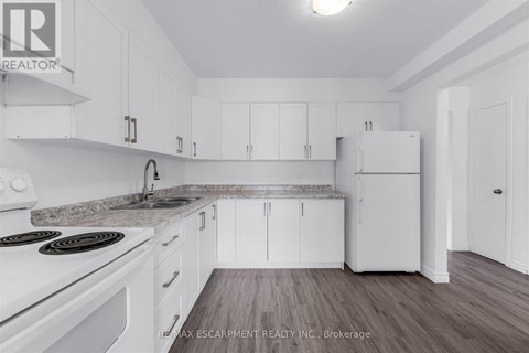 A white kitchen with a stove top oven and a refrigerator.