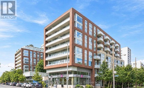 A large, modern apartment building with multiple balconies and a clear blue sky above.