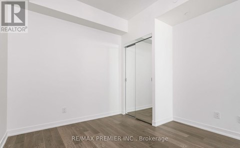 A room with a white wall and a wooden floor with a door.
