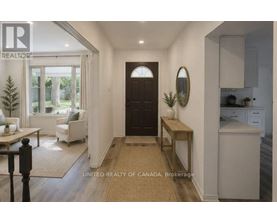 A brokerage image of a well-lit hallway with a bench, a door, and a mirror.