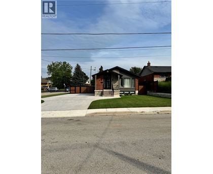 A house with a brown roof and a white fence is in the image.