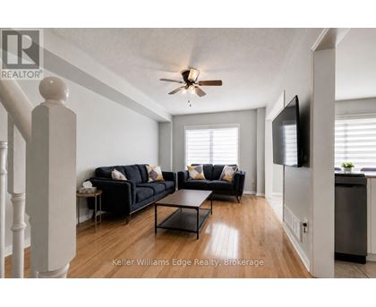 A living room with a black couch and a ceiling fan.