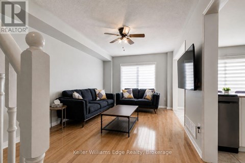 A living room with a black couch and a ceiling fan.