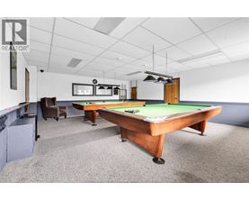 A pool table in a room with a chair and a cabinet.