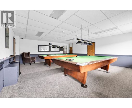 A pool table in a room with a chair and a cabinet.