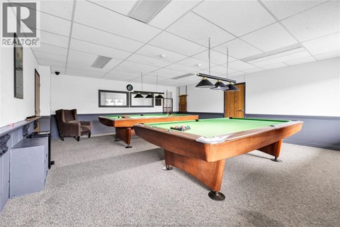 A pool table in a room with a chair and a cabinet.