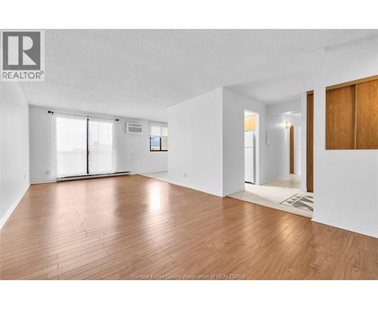 A spacious room with wooden flooring and white walls.