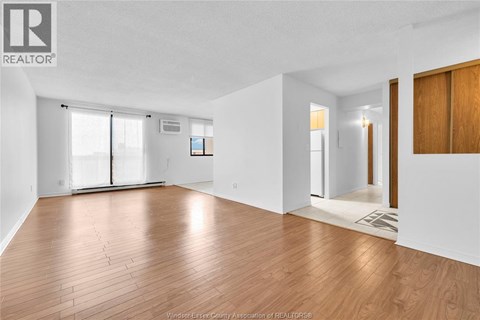 A spacious room with wooden flooring and white walls.