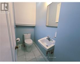 A bathroom with a toilet, sink and mirror.