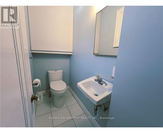 A bathroom with a toilet, sink and mirror.