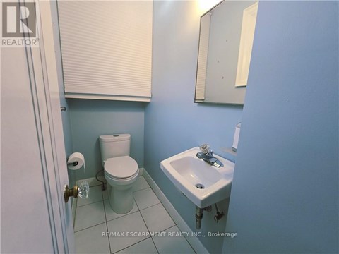 A bathroom with a toilet, sink and mirror.