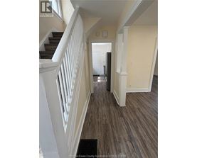 A hallway with a staircase and a door at the end.