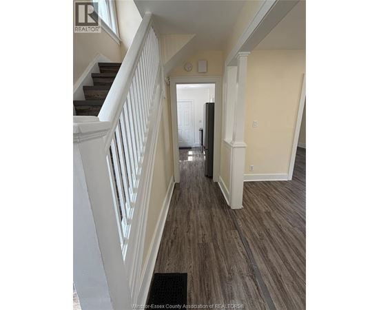 A hallway with a staircase and a door at the end.