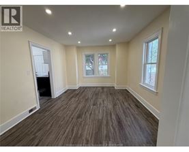 A room with wooden flooring and a window with a view of trees.