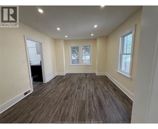 A room with wooden flooring and a window with a view of trees.