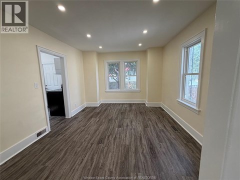A room with wooden flooring and a window with a view of trees.