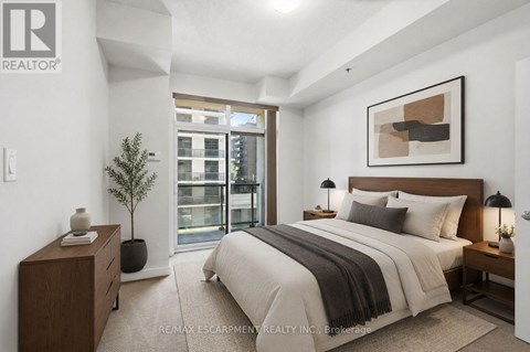 A bedroom with a large bed, a nightstand, and a plant.